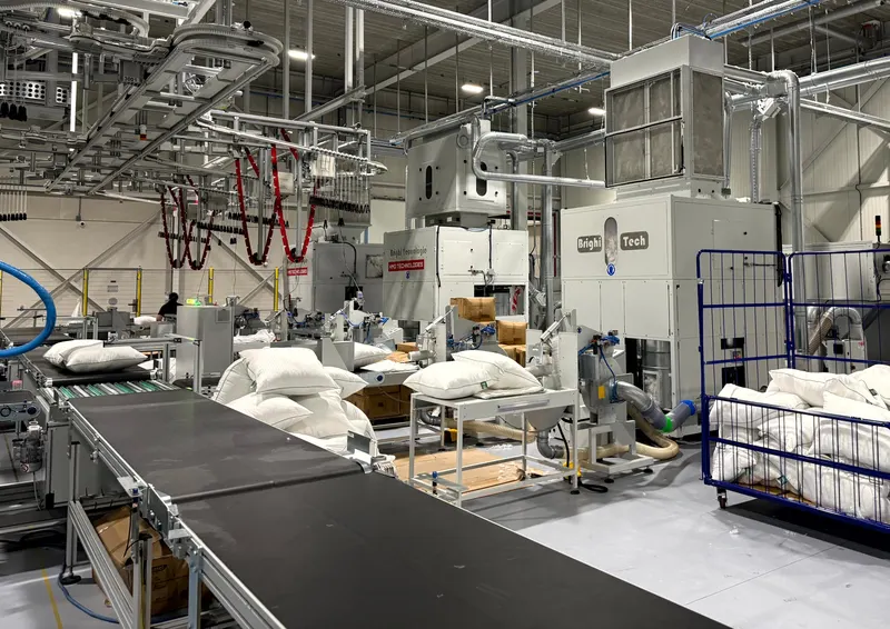 Die automatische Füllanlage im Werk von HMG: weiße Kissen auf dem Förderband neben den Füllmaschinen