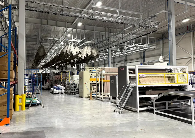 The HMG production hall: duvets on the hook line above a quilting line, with racking along the wall